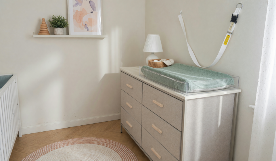A tall fabric dresser secured with a wall-anchor strap in a child's room, illustrating tip-over prevention