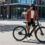 Person wearing a helmet standing next to a modern e-bike on a sunny city street