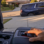 Pickup truck and SUV parked on a sloped driveway with a driver engaging the electronic parking brake