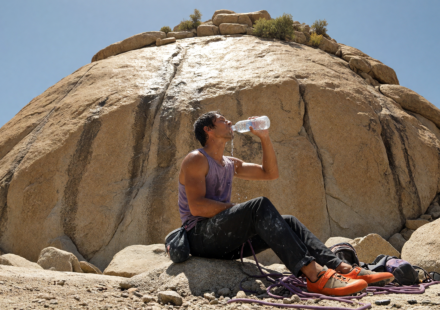 Rock climber drinking water at a sunlit granite crag on a hot day