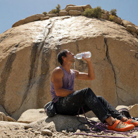 Rock climber drinking water at a sunlit granite crag on a hot day