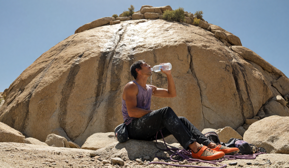 Rock climber drinking water at a sunlit granite crag on a hot day