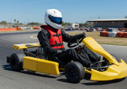 Kart racer in helmet and rib protector in a go-kart on a sunny track