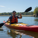 Kayaker in a PFD paddling a kayak on a calm sunny lake