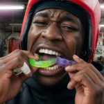 Athlete inserting a sports mouthguard, close-up, gym background