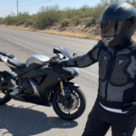 Motorcyclist in a ventilated mesh armored jacket and full-face helmet by a bike