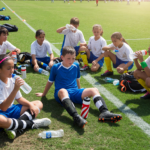 Youth soccer players taking a water break on a sunny green field
