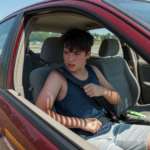 Teenage driver buckling a seatbelt inside a car on a summer day