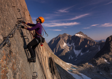 Climber on a via ferrata clipped to a steel cable on a mountain cliff