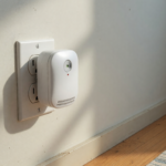 A white plug-in carbon monoxide detector in a home wall outlet, illustrating the CPSC KH158 detector warning