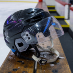 Ice hockey helmet with a clear polycarbonate half-visor face shield on a rink bench