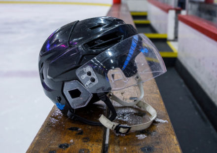 Ice hockey helmet with a clear polycarbonate half-visor face shield on a rink bench