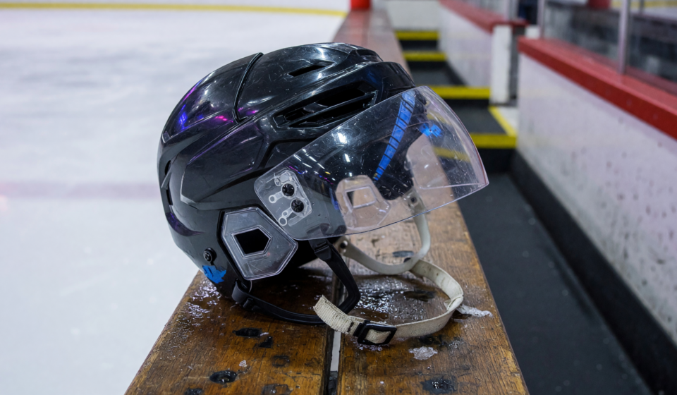 Ice hockey helmet with a clear polycarbonate half-visor face shield on a rink bench