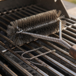 Metal wire-bristle grill brush on a barbecue grate, illustrating the Cuisinart grill brush recall over bristle ingestion hazard