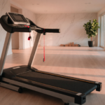 A treadmill in a bright home gym with a clear runway behind the belt and the safety key tether clipped to the handrail
