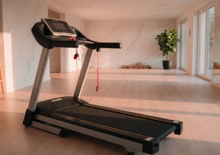 A treadmill in a bright home gym with a clear runway behind the belt and the safety key tether clipped to the handrail