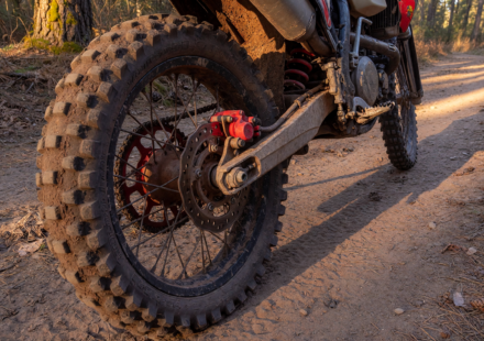 Off-road enduro dirt motorcycle on a trail with the rear brake caliper in focus