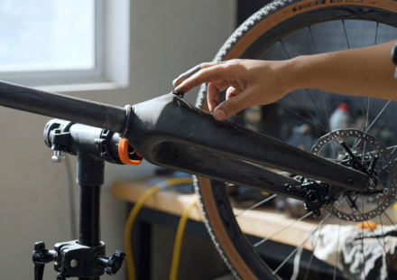 Mechanic inspecting the carbon fiber front fork and crown of a gravel bicycle on a repair stand