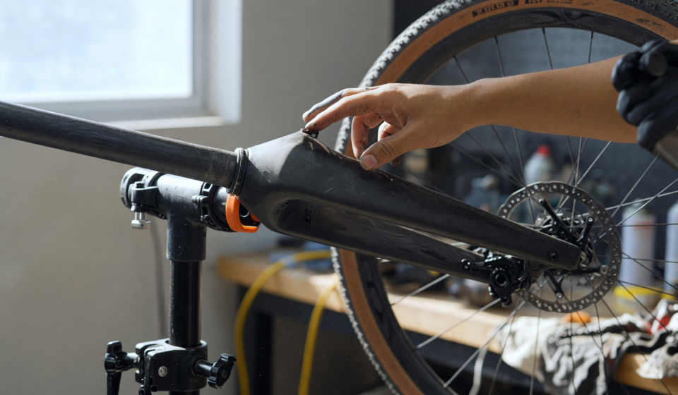 Mechanic inspecting the carbon fiber front fork and crown of a gravel bicycle on a repair stand