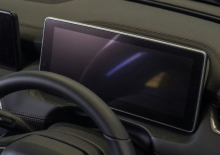 Dark, blank digital instrument cluster behind a car steering wheel, illustrating the Toyota Camry Hybrid recall