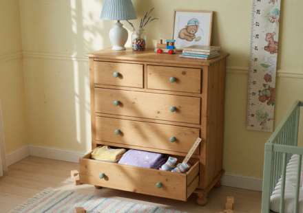 A tall six-drawer wooden dresser against a wall in a child's room with a lower drawer open, illustrating tip-over hazard