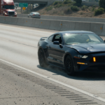 A Ford Mustang pulled onto a highway shoulder with hazard lights on after a power-loss issue