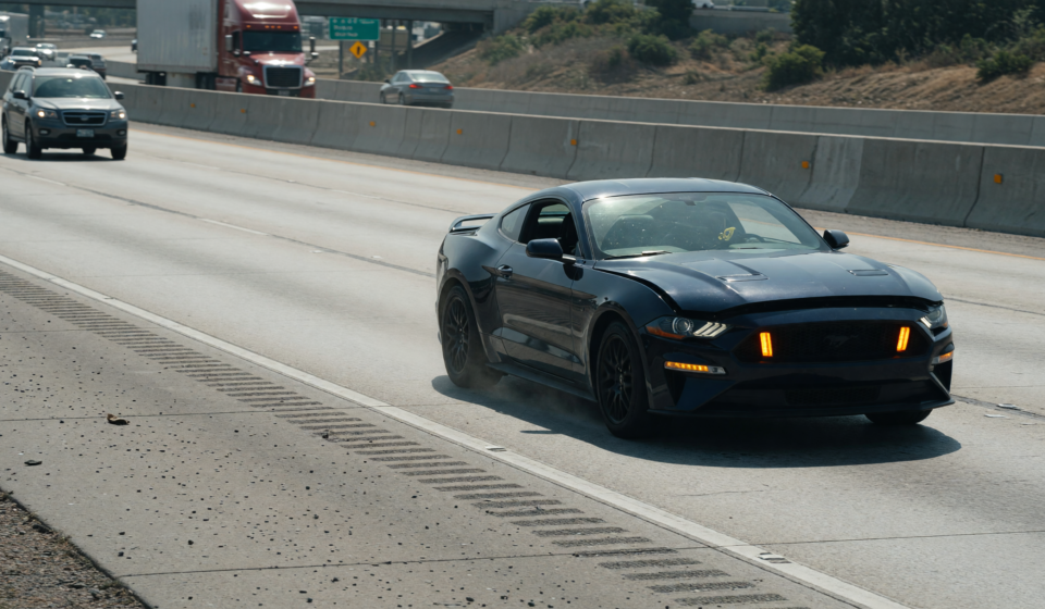 A Ford Mustang pulled onto a highway shoulder with hazard lights on after a power-loss issue