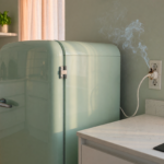 A retro compact refrigerator in a home kitchen with a faint wisp of smoke near the outlet, illustrating the Galanz refrigerator recall fire hazard