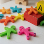 Small colorful magnetic stick figure toys scattered beside wooden building blocks, illustrating a magnetic toy recall over magnet ingestion risk