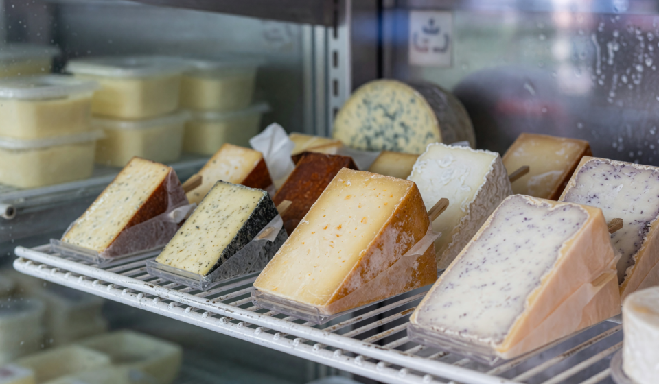 Wrapped artisan cheese wedges on a refrigerated grocery store shelf